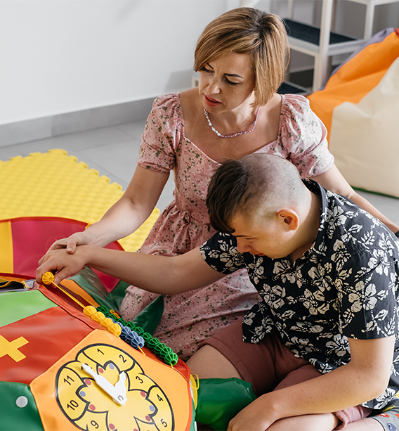 Care provider assisting a child with autism in a comfortable home environment.